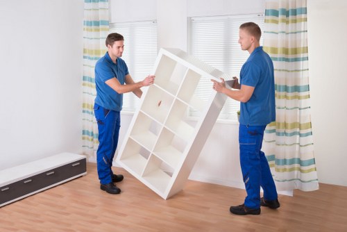 Professional movers carrying furniture through a Brentford property