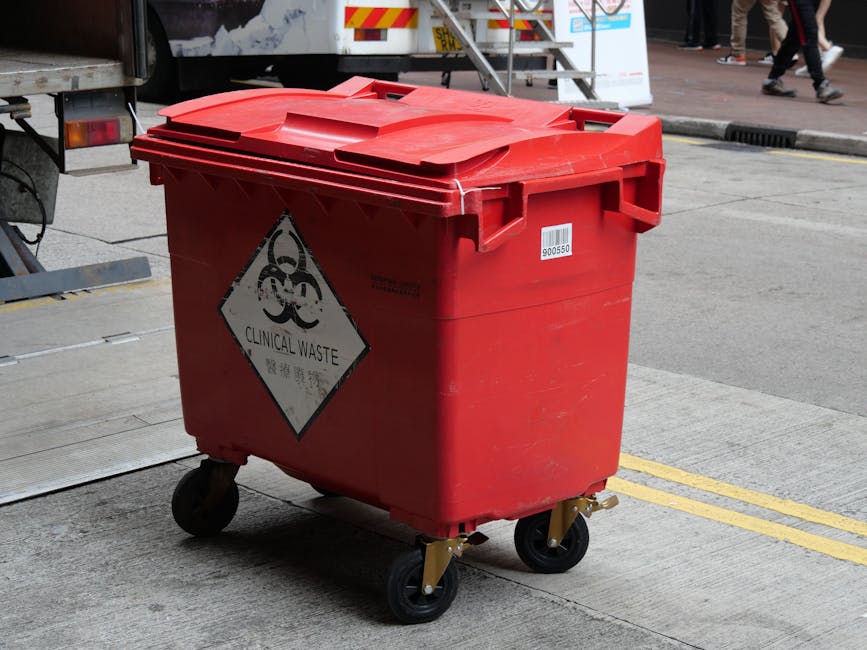 A close-up view of a pile of cardboard boxes, some with printed labels and packing tape, being consumed by a small fire with visible orange flames and grey smoke. The boxes are partially burnt, with e